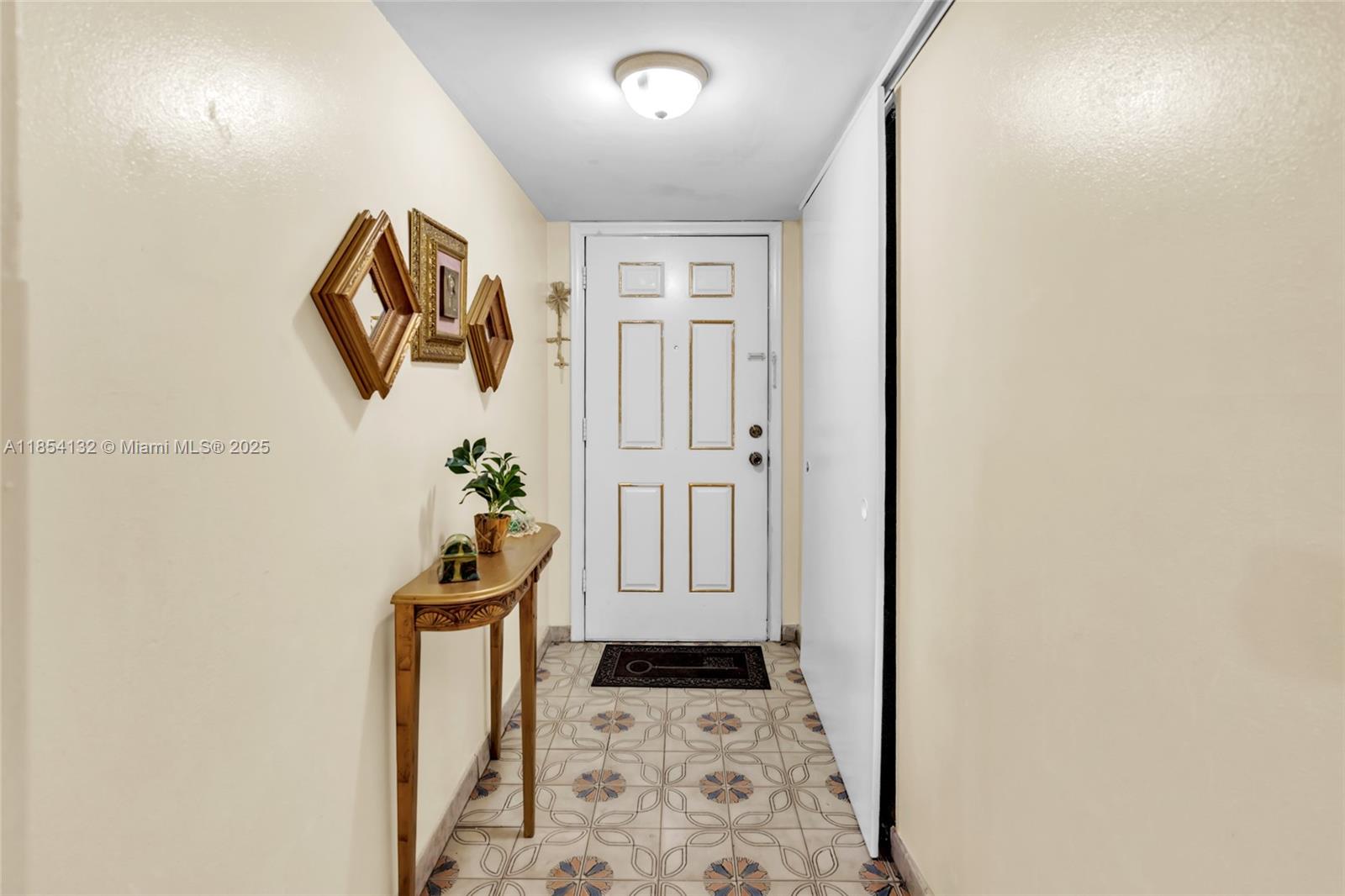 1855 West 62nd Street, Unit E306 Hialeah, FL 33012 - Photo 6 of 35 a hallway with table and front door