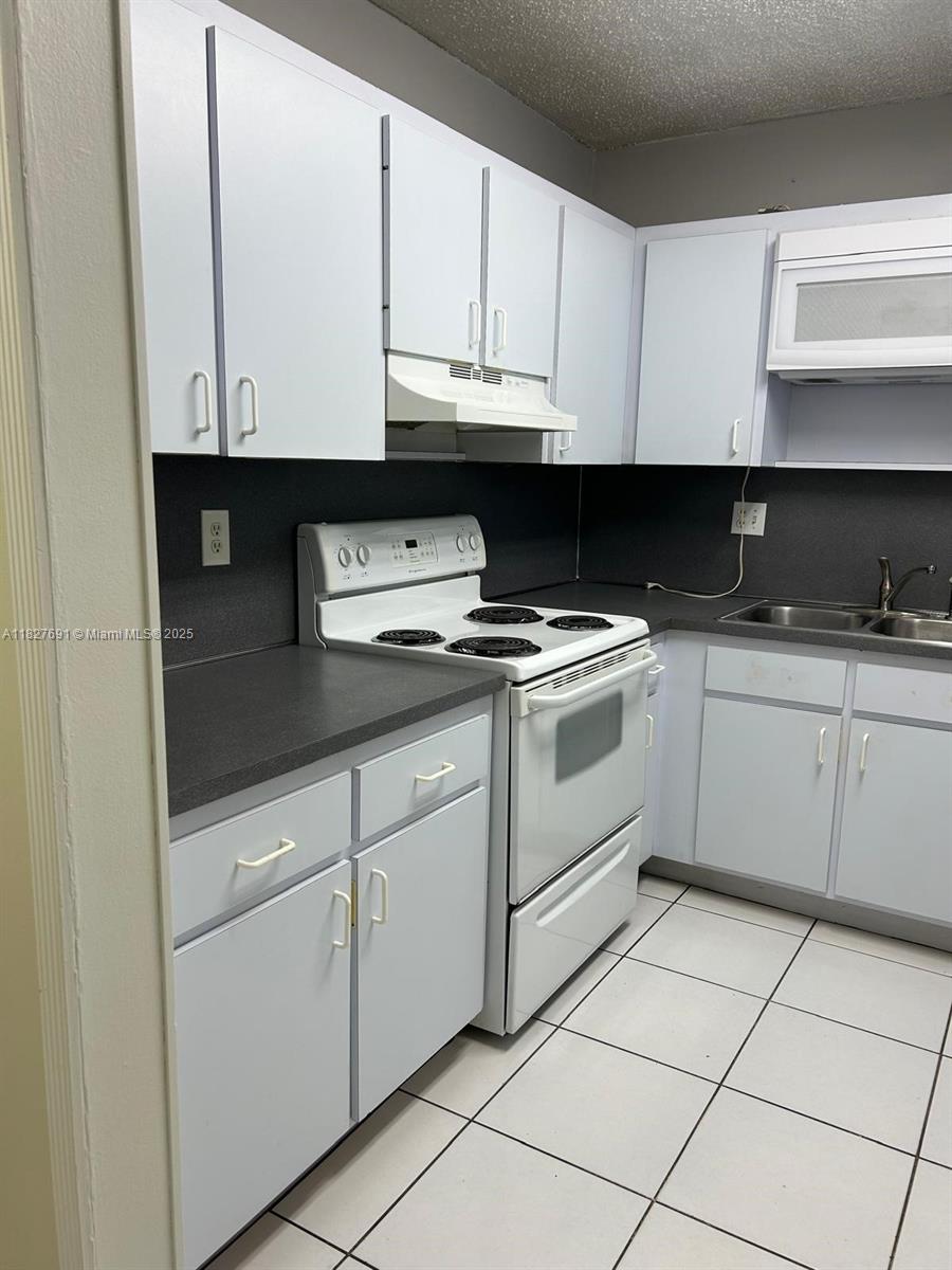 6125 West 20th Avenue, Unit 217 Hialeah, FL 33012 - Photo 6 of 16 a kitchen with granite countertop white cabinets and white appliances