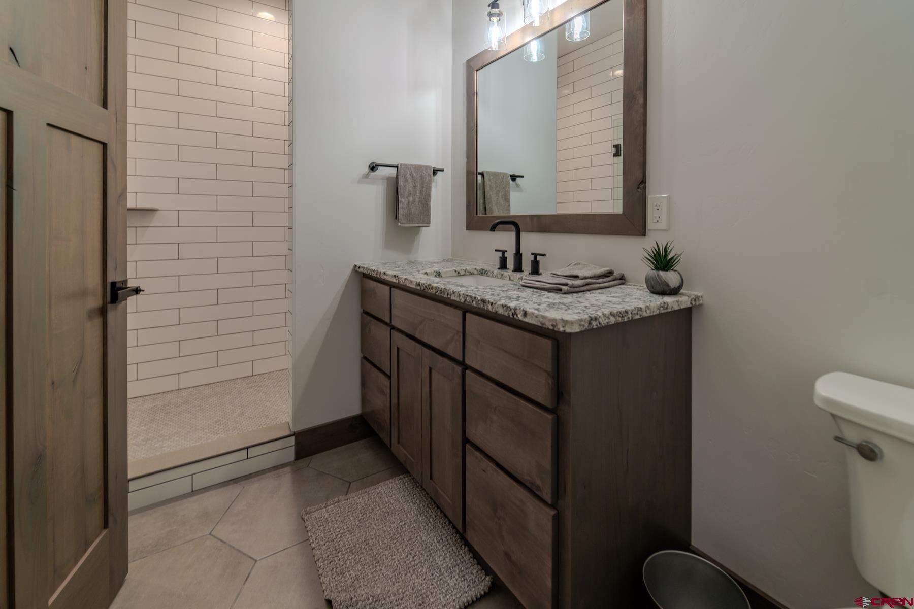 1700 Thoroughbred Road Durango, CO 81303 - Photo 38 of 45 a bathroom with a granite countertop sink a toilet and mirror