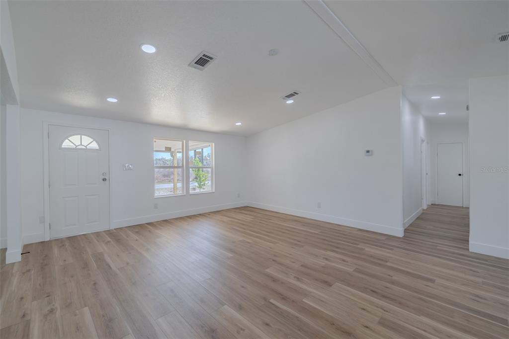 8301 Henry George Road Plant City, FL 33567 - Photo 12 of 51 an empty room with wooden floor and windows