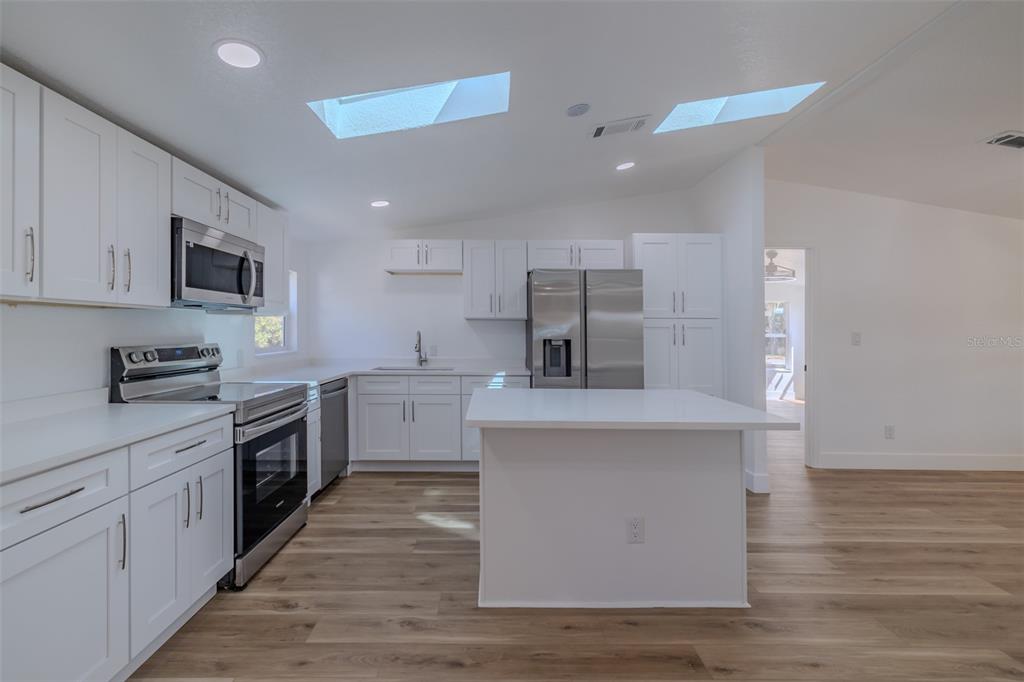 8301 Henry George Road Plant City, FL 33567 - Photo 14 of 51 a large kitchen with stainless steel appliances granite countertop a stove top oven a sink dishwasher and a refrigerator