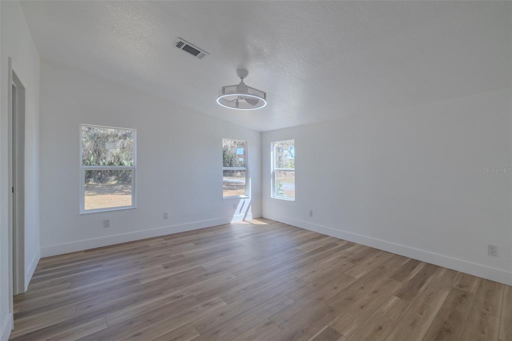 8301 Henry George Road Plant City, FL 33567 - Photo 19 of 51 an empty room with wooden floor and windows