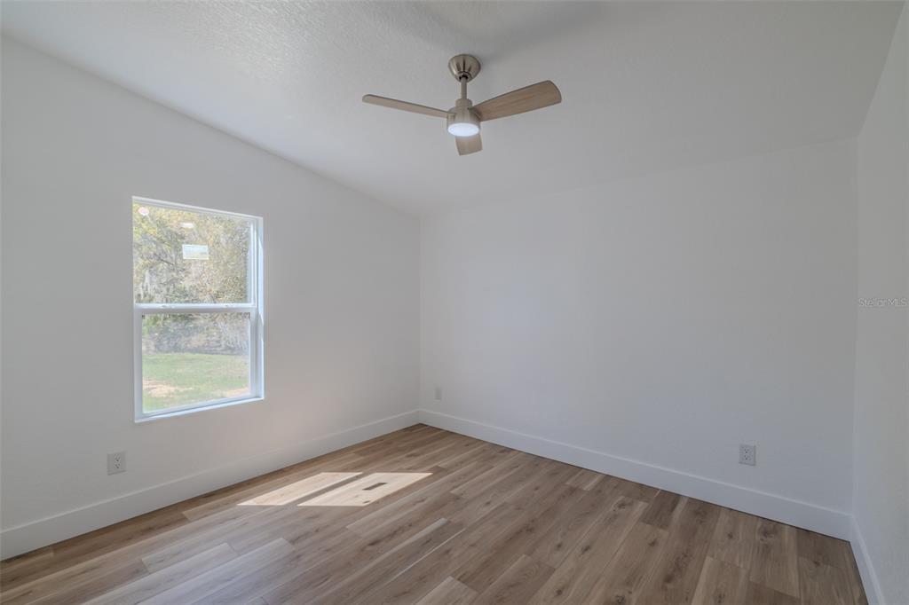 8301 Henry George Road Plant City, FL 33567 - Photo 34 of 51 an empty room with wooden floor ceiling fan and windows