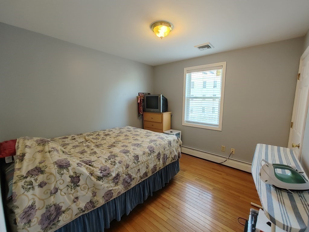 389 4th Street Fall River, MA 02721 - Photo 20 of 30 a bedroom with a bed and wooden floor