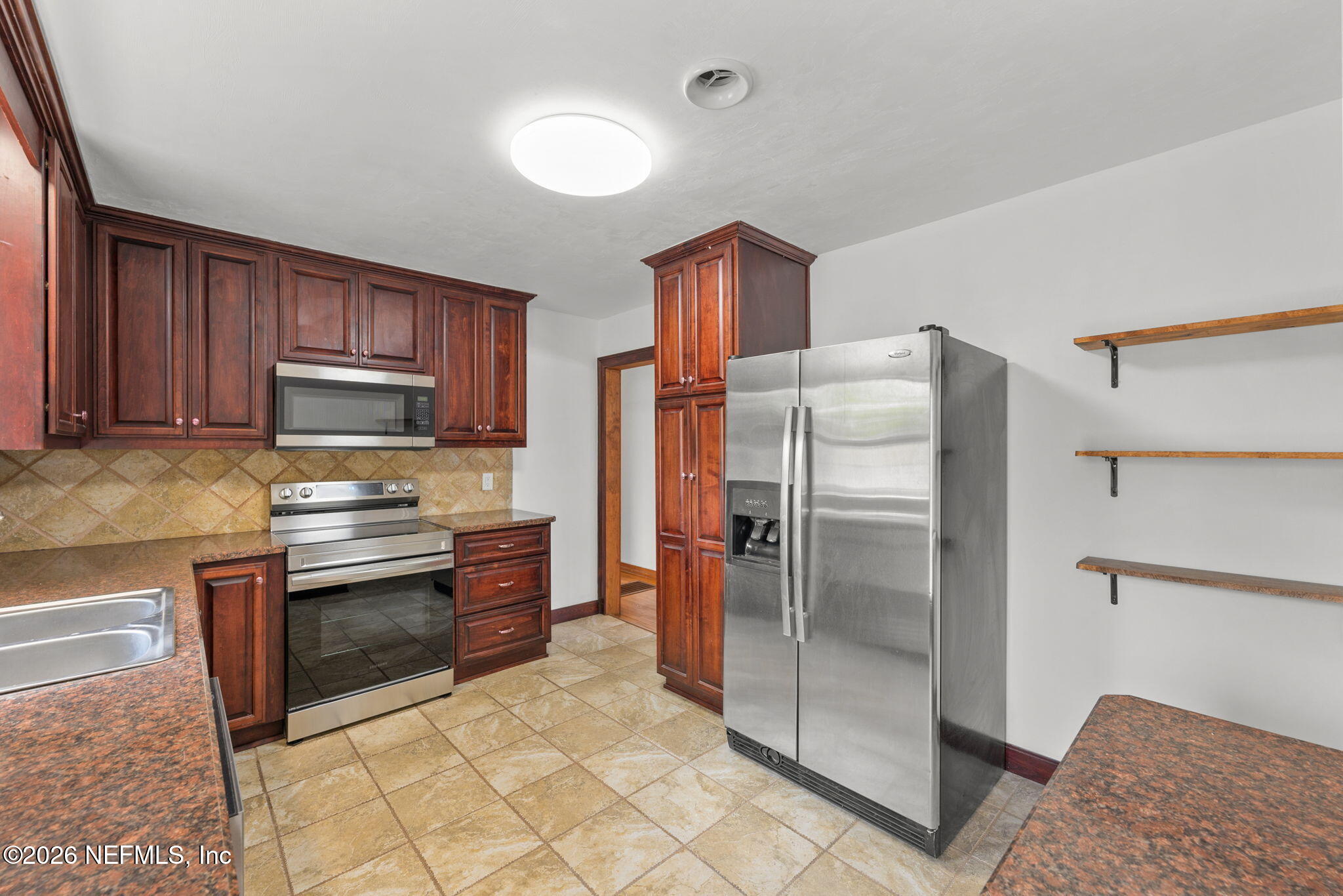 2003 Laurel Street Palatka, FL 32177 - Photo 10 of 31 a kitchen with granite countertop a refrigerator and a stove top oven