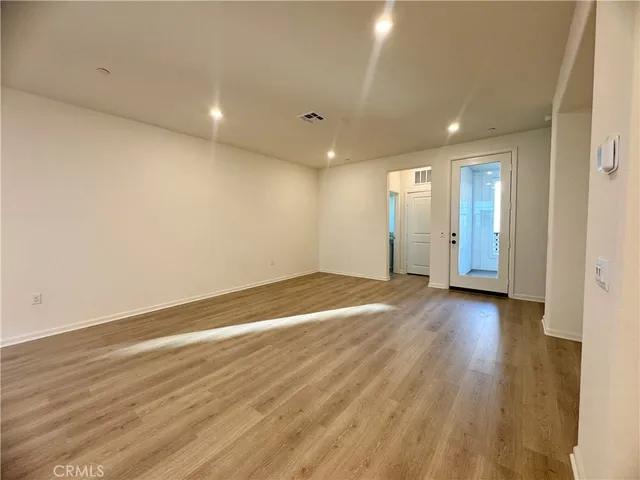 an empty room with wooden floor and bathroom
