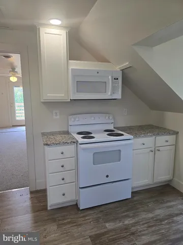 a kitchen with granite countertop a stove oven and white cabinets