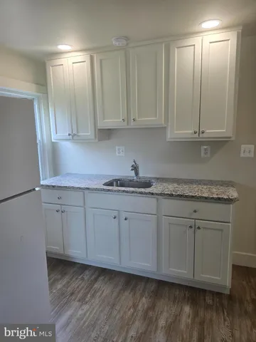 a kitchen with granite countertop white cabinets and a sink