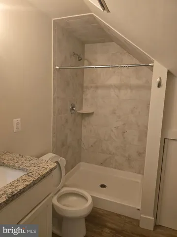 a bathroom with a granite countertop bathtub shower and toilet