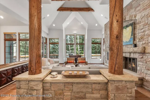 a living room with furniture large windows and wooden floor