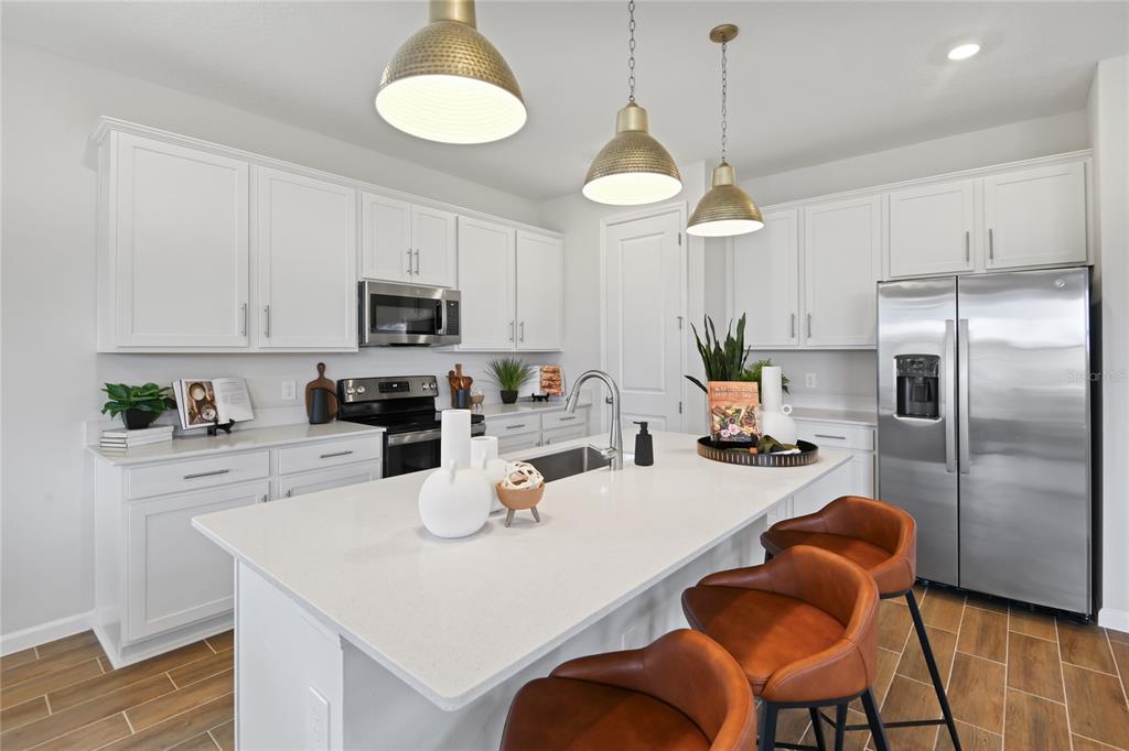 5131 Spring Maiden Circle Apollo Beach, FL 33572 - Photo 6 of 25 a kitchen with stainless steel appliances granite countertop a refrigerator a stove a sink dishwasher a dining table and chairs with wooden floor