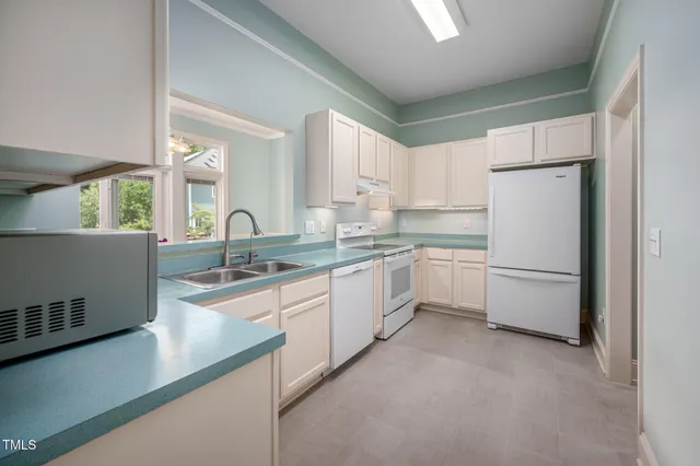 a kitchen with granite countertop white cabinets and white appliances