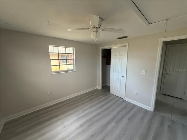 an empty room with wooden floor closet and windows