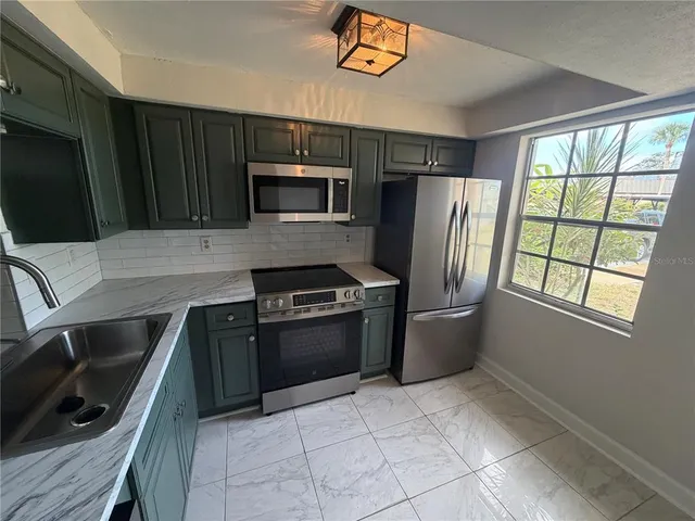 a kitchen with stainless steel appliances granite countertop a refrigerator stove and microwave