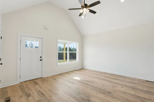 an empty room with wooden floor closet and windows