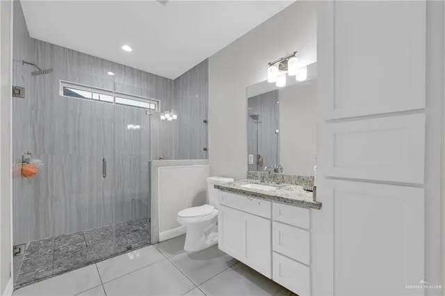 a bathroom with a granite countertop sink a toilet and shower