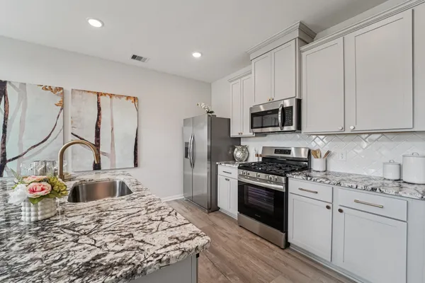 a kitchen with stainless steel appliances granite countertop a stove top oven a sink dishwasher a refrigerator and cabinets with wooden floor