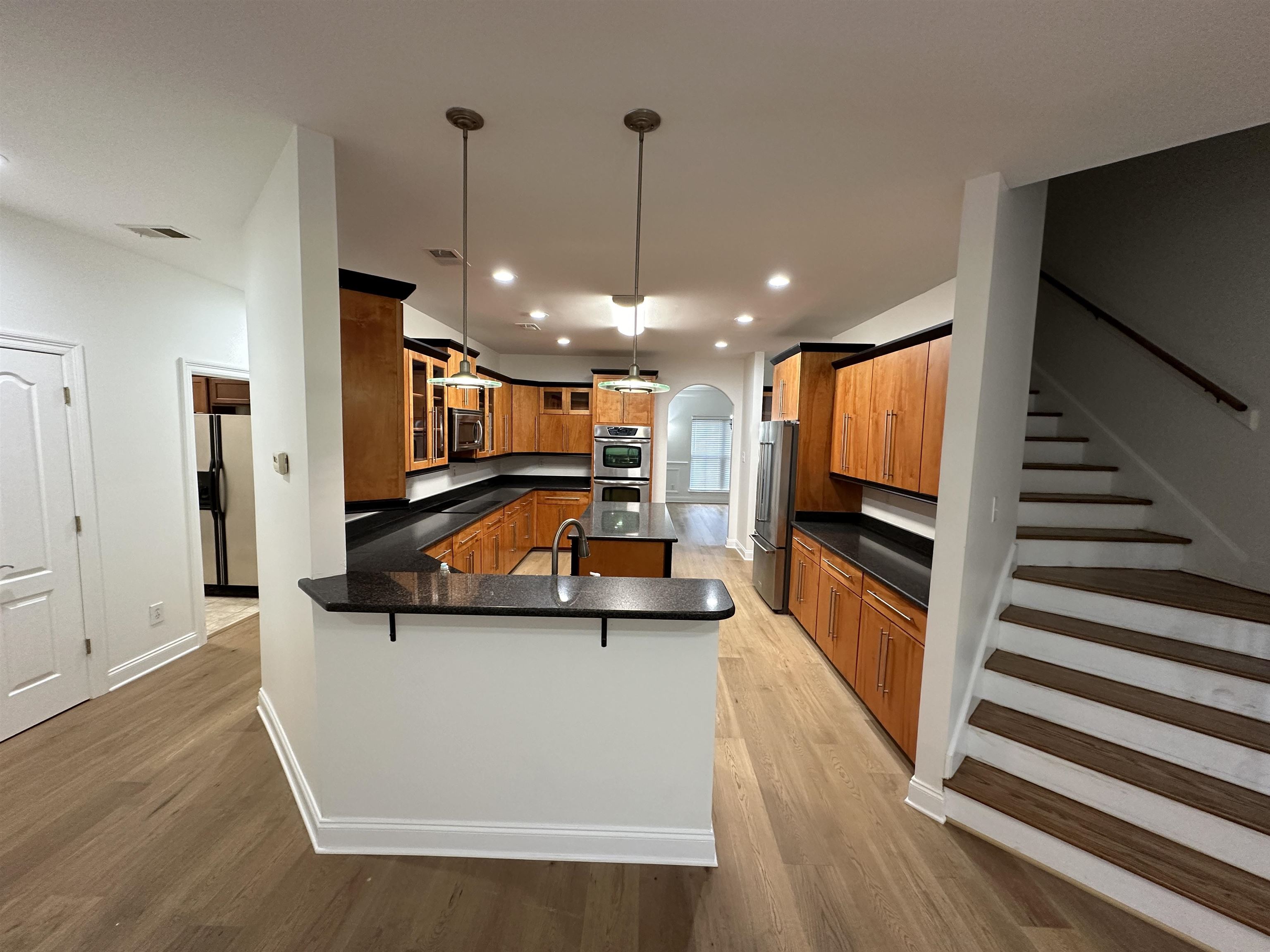 55 Hickory Nut Road Piperton, TN 38017 - Photo 6 of 40 Kitchen with brown cabinets, arched walkways, appliances with stainless steel finishes, a peninsula, and light wood finished floors