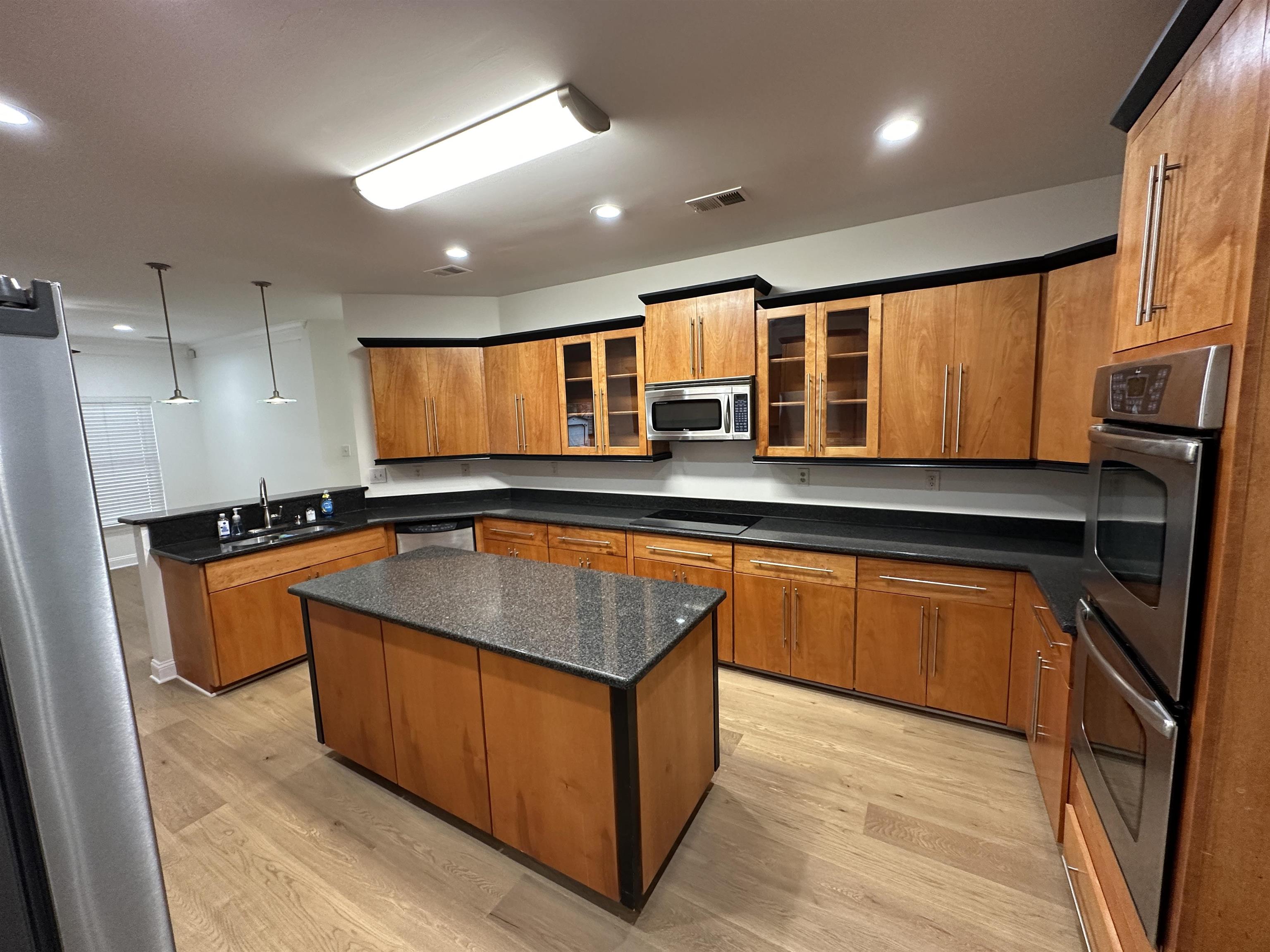 55 Hickory Nut Road Piperton, TN 38017 - Photo 7 of 40 Kitchen featuring a peninsula, brown cabinetry, appliances with stainless steel finishes, and a sink