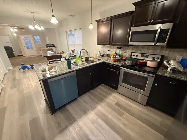 a kitchen with stainless steel appliances kitchen island granite countertop a sink stove and microwave