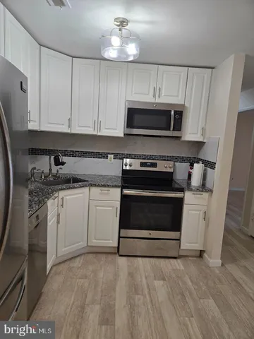 a kitchen with granite countertop a stove a sink and a microwave