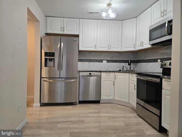 a kitchen with stainless steel appliances granite countertop a stove a refrigerator and a microwave