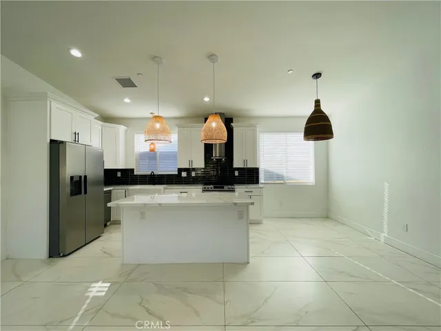 a kitchen with stainless steel appliances kitchen island granite countertop a refrigerator and a sink