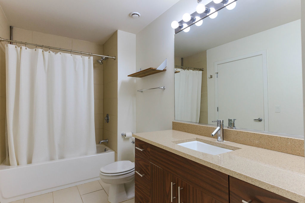 1224 West Van Buren Street, Unit 707 Chicago, IL 60607 - Photo 12 of 15 a bathroom with a granite countertop sink toilet a large mirror and shower curtain