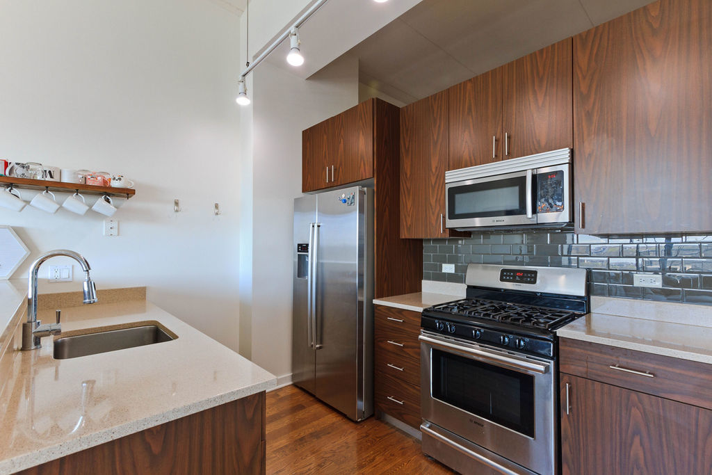1224 West Van Buren Street, Unit 707 Chicago, IL 60607 - Photo 5 of 15 a kitchen with stainless steel appliances granite countertop a sink stove and refrigerator