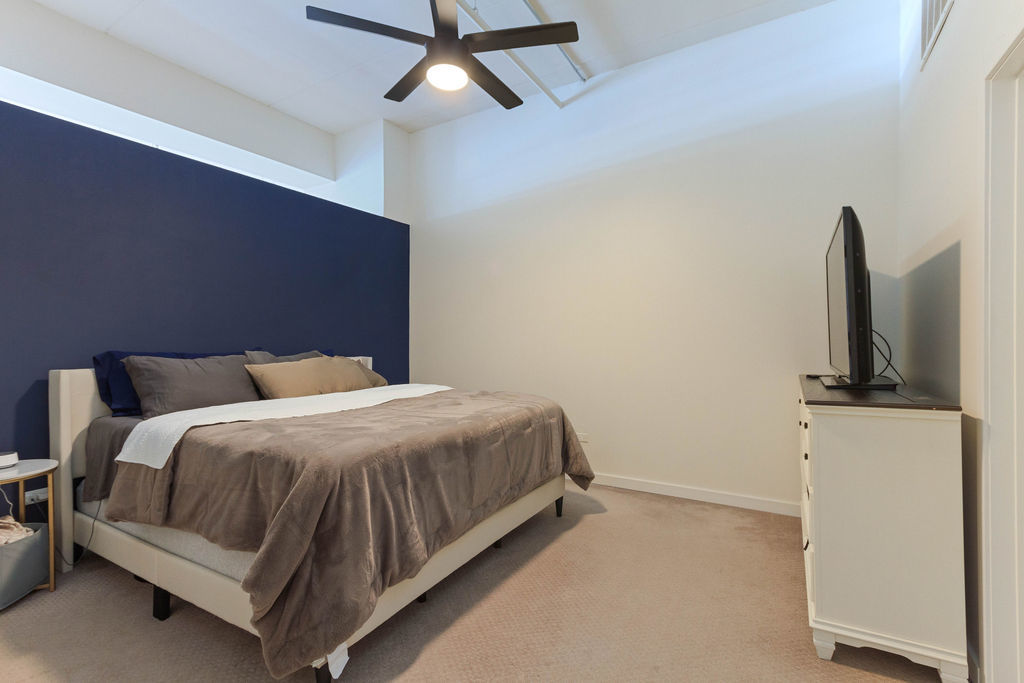 1224 West Van Buren Street, Unit 707 Chicago, IL 60607 - Photo 9 of 15 a spacious bedroom with a bed and a flat screen tv