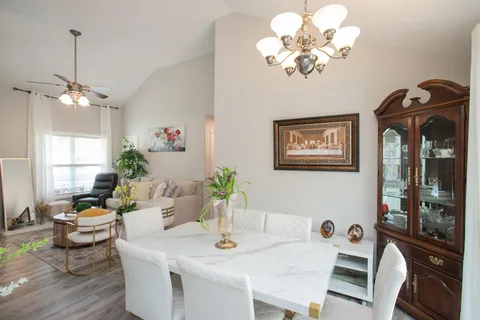 a view of a dining room with furniture a chandelier a window and wooden floor