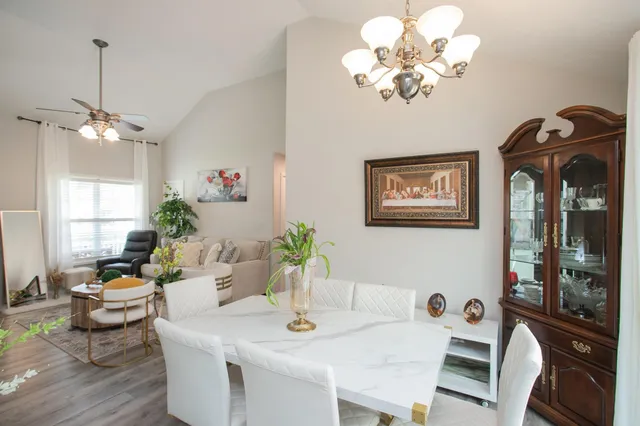 a view of a dining room with furniture a chandelier a window and wooden floor