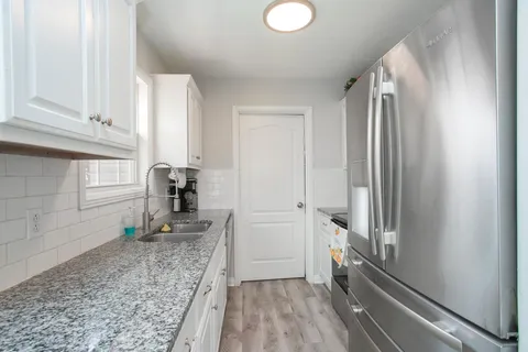 a kitchen with granite countertop a refrigerator and a sink