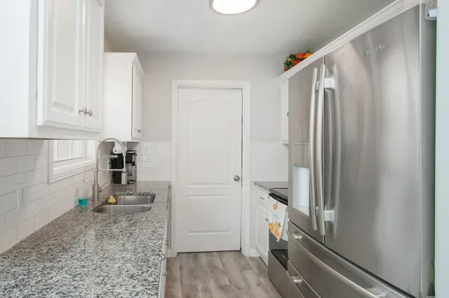a kitchen with granite countertop a refrigerator and a sink