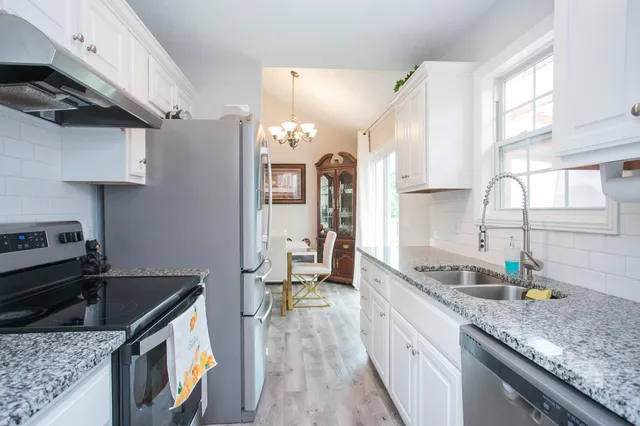 a kitchen with granite countertop a sink a stove and cabinets