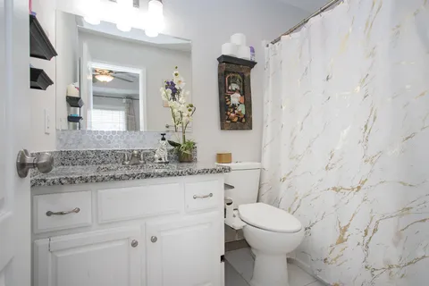 a bathroom with a granite countertop toilet sink and mirror