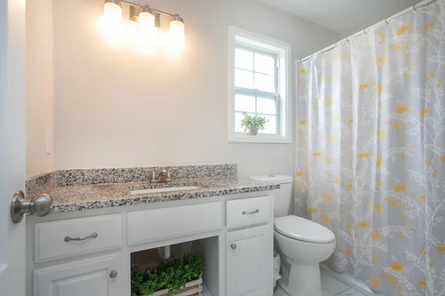 a bathroom with a granite countertop sink a toilet and shower curtain