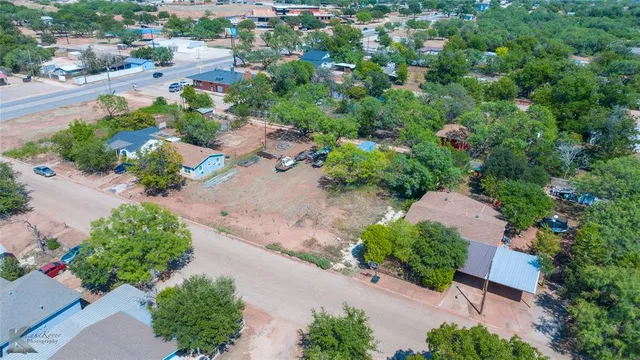 an aerial view of a house with a yard and trees all around
