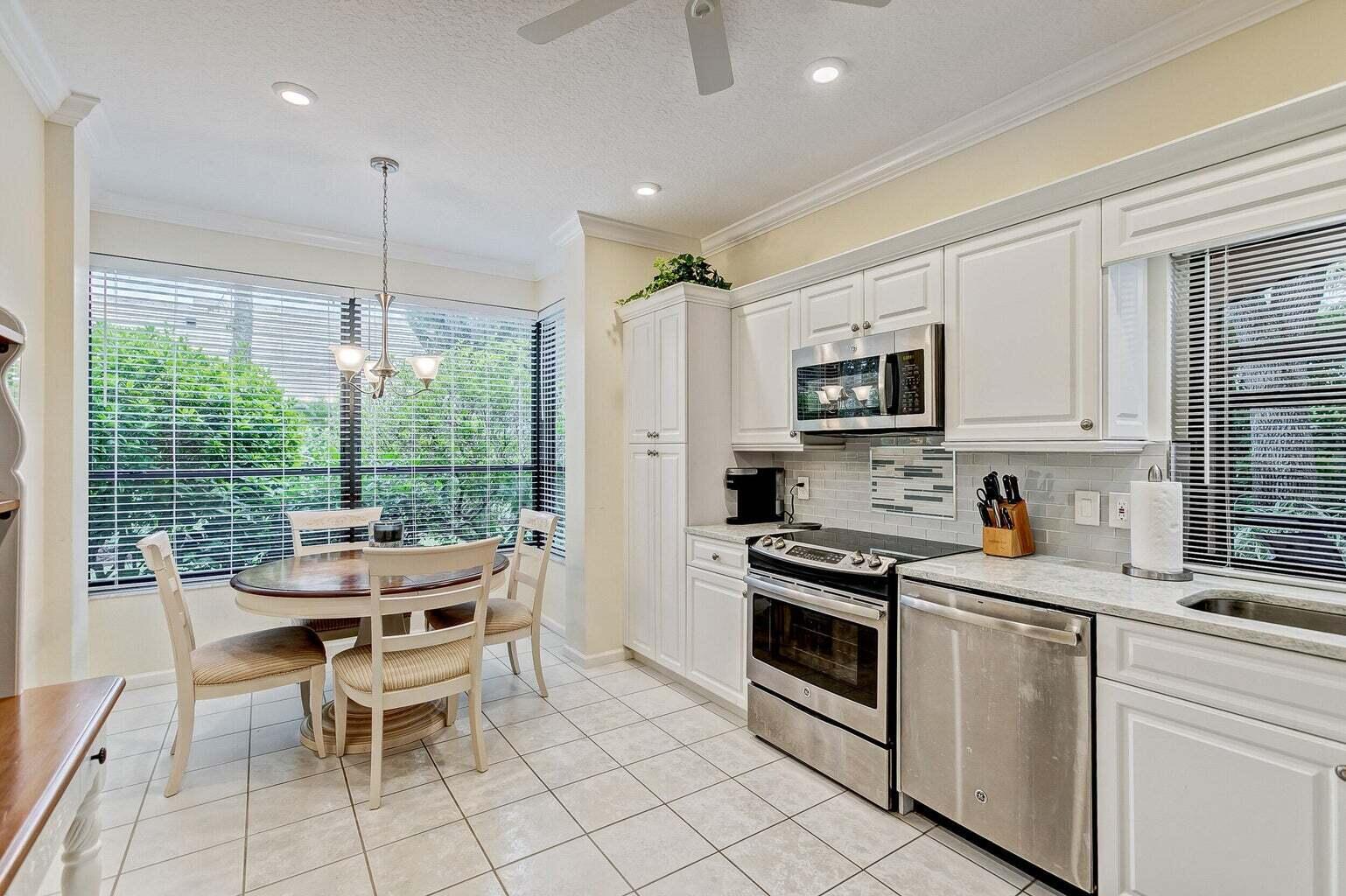 16151 West Bay Drive, Unit 161 Jupiter, FL 33477 - Photo 12 of 19 a kitchen with stainless steel appliances a stove a sink a microwave a dining table and chairs