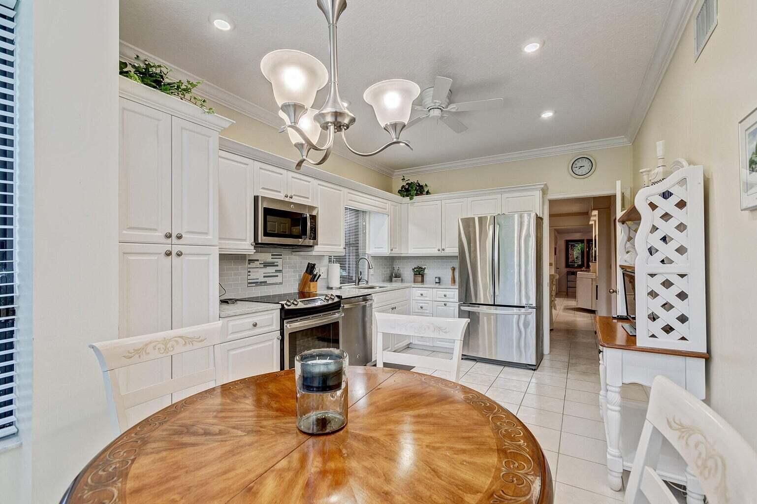 16151 West Bay Drive, Unit 161 Jupiter, FL 33477 - Photo 3 of 19 a kitchen with stainless steel appliances granite countertop a sink a stove a dining table and chairs