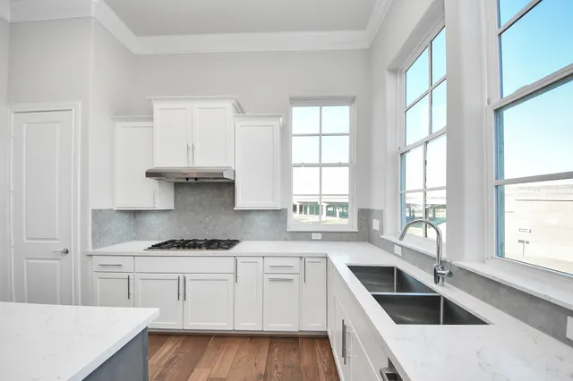 a kitchen with granite countertop a sink and white cabinets