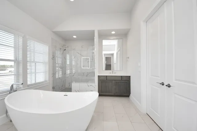 a large tub sitting in a en suite bathroom with a tub sink shower and mirror