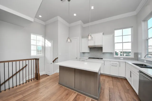 a large kitchen with stainless steel appliances granite countertop a stove a sink dishwasher and white cabinets with wooden floor