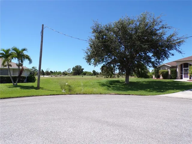 a view of a house with a big yard and palm trees