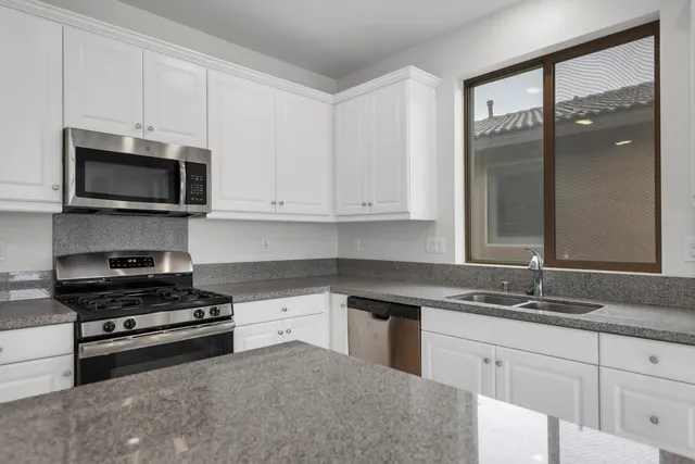 a kitchen with granite countertop white cabinets stainless steel appliances and a sink