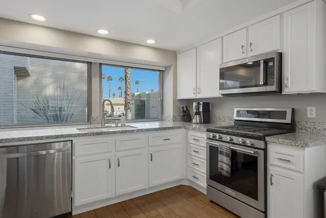 a kitchen with granite countertop wooden cabinets stainless steel appliances and a sink