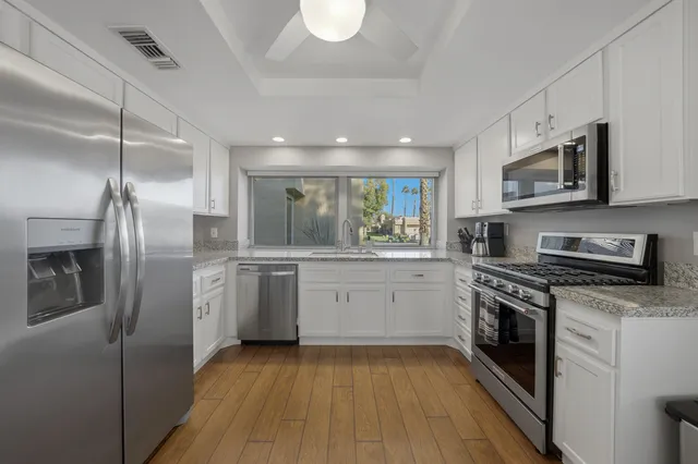 a kitchen with stainless steel appliances granite countertop a stove a sink and a refrigerator