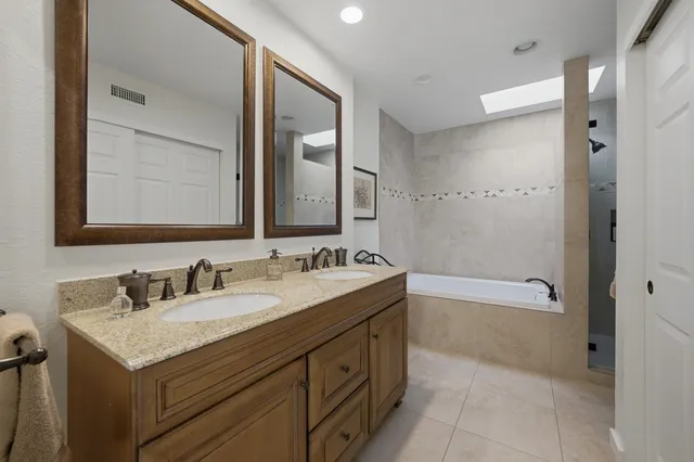 a bathroom with a sink double vanity granite tub shower and a mirror