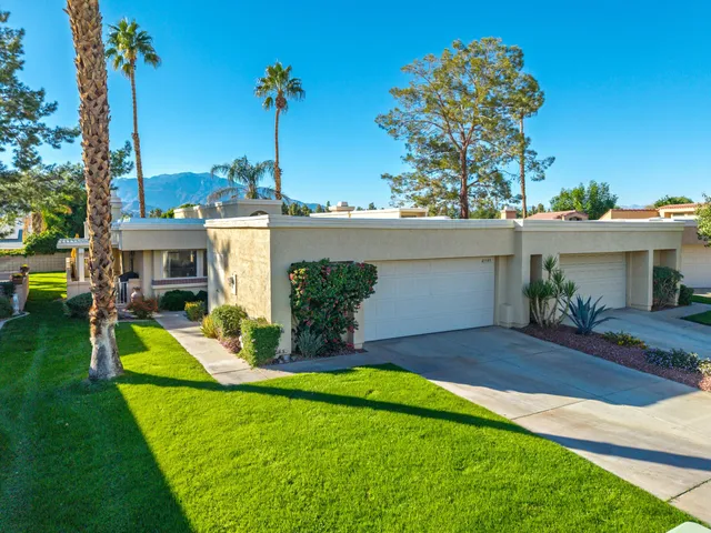 a view of a house with a yard and palm trees