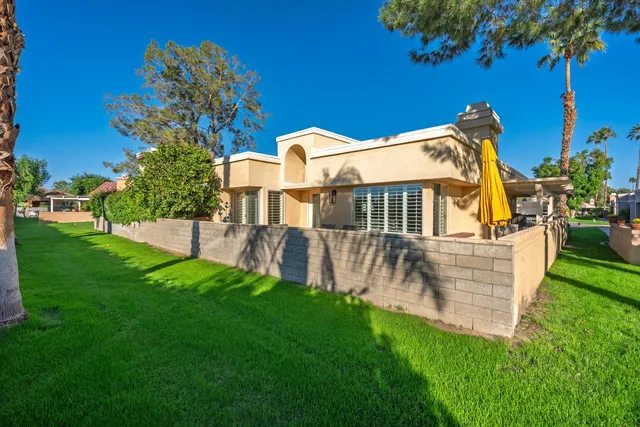 a view of a house with a yard and a large tree